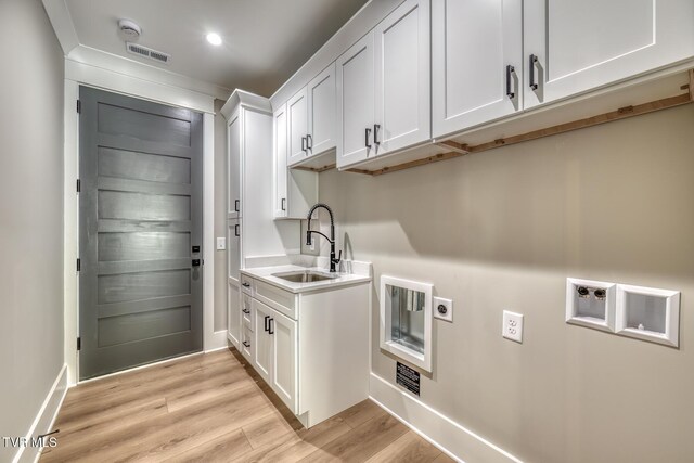 washroom featuring cabinets, light hardwood / wood-style floors, sink, hookup for a washing machine, and hookup for an electric dryer