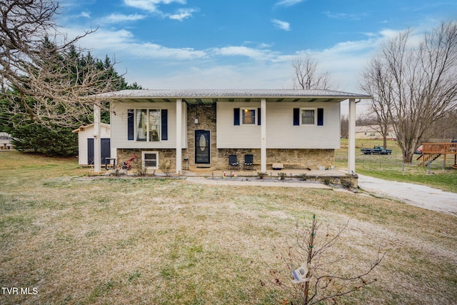 split foyer home featuring a front lawn and an outdoor structure