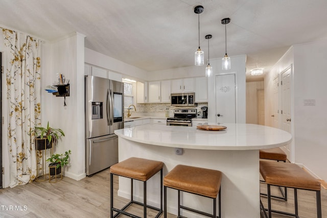 kitchen with white cabinetry, sink, a center island, light hardwood / wood-style flooring, and appliances with stainless steel finishes