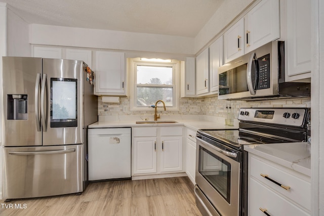 kitchen featuring appliances with stainless steel finishes, tasteful backsplash, sink, light hardwood / wood-style flooring, and white cabinets