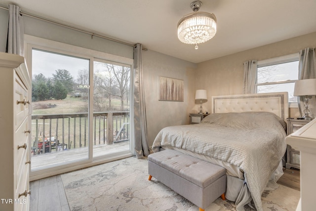 bedroom featuring access to exterior, wood-type flooring, and a notable chandelier