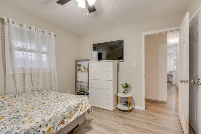 bedroom with a textured ceiling, light wood-type flooring, and ceiling fan