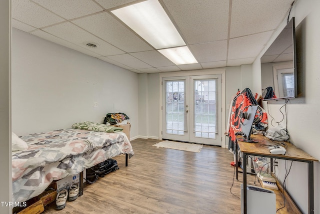 bedroom featuring a paneled ceiling, hardwood / wood-style floors, access to outside, and french doors