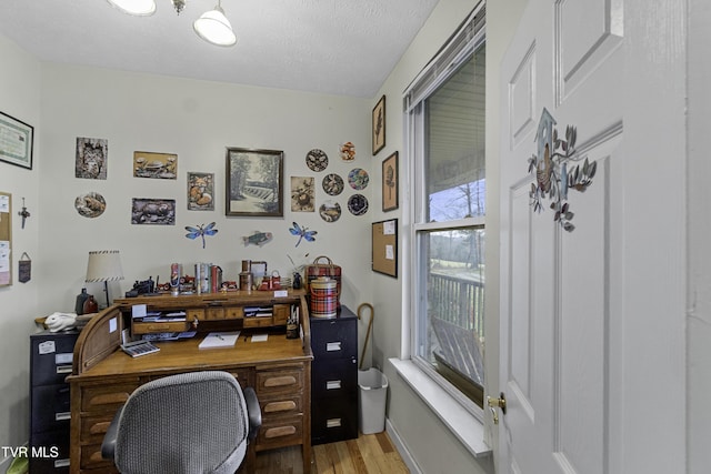 office area with a healthy amount of sunlight, wood-type flooring, and a textured ceiling