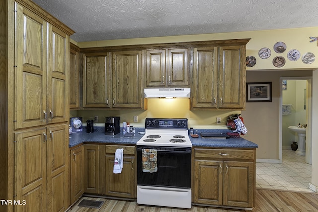 kitchen with light wood-type flooring, a textured ceiling, and white electric range