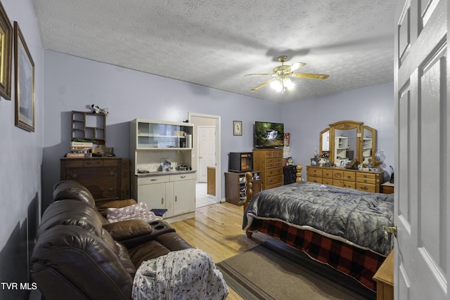 bedroom with ceiling fan, light hardwood / wood-style flooring, and a textured ceiling