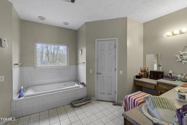 bathroom with tile patterned flooring, vanity, a relaxing tiled tub, and a textured ceiling