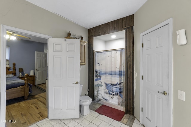 bathroom with tile patterned floors, ceiling fan, toilet, and walk in shower