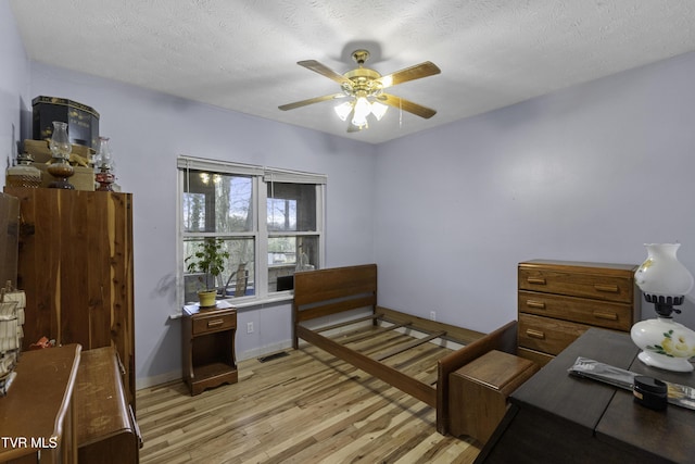 bedroom with a textured ceiling, light hardwood / wood-style floors, and ceiling fan