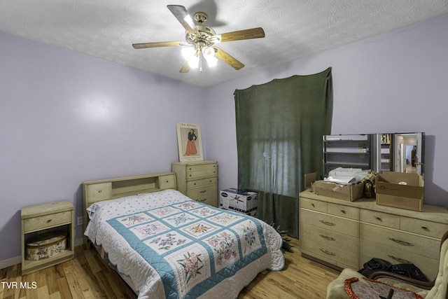 bedroom with ceiling fan, light wood-type flooring, and a textured ceiling