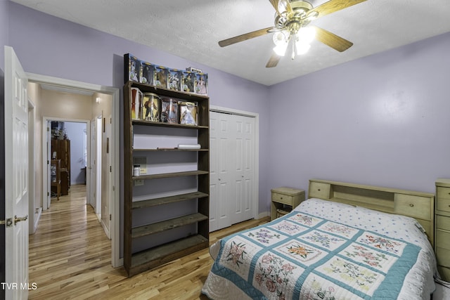 bedroom featuring ceiling fan, light hardwood / wood-style floors, a textured ceiling, and a closet