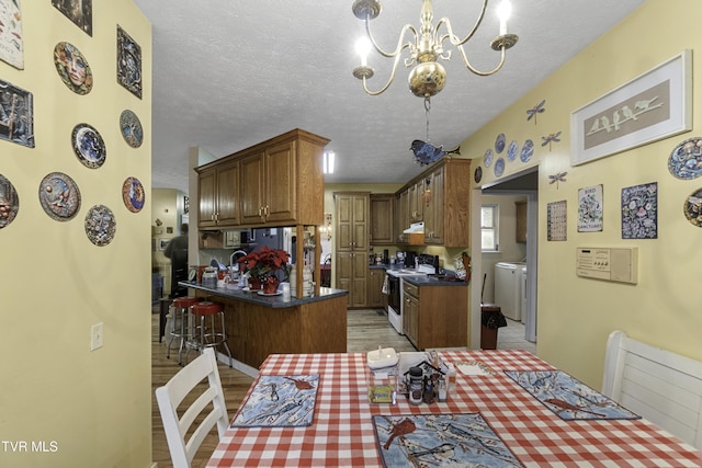 kitchen with electric range, a notable chandelier, pendant lighting, a textured ceiling, and a kitchen bar