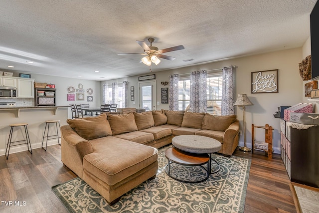 living room featuring ceiling fan, dark wood-type flooring, and a textured ceiling