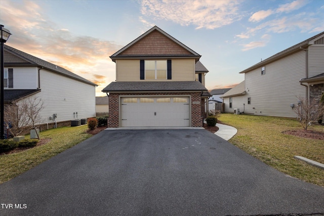 view of front of home with a garage, a front yard, brick siding, and aphalt driveway