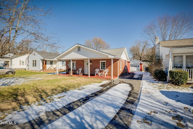 view of front of property featuring a porch, a yard, a garage, and an outbuilding