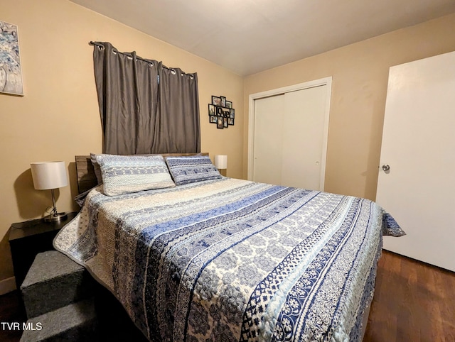 bedroom with dark wood-type flooring and a closet