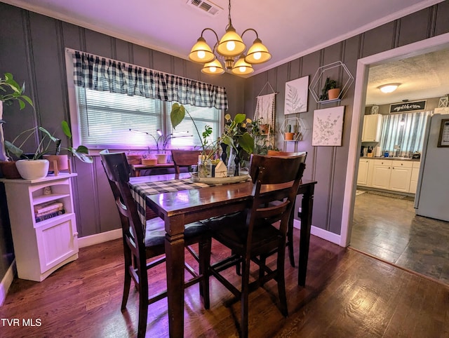 dining space featuring dark hardwood / wood-style flooring, an inviting chandelier, and crown molding