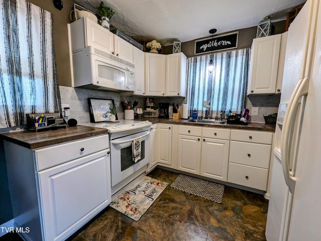 kitchen featuring sink, white appliances, a textured ceiling, and white cabinets