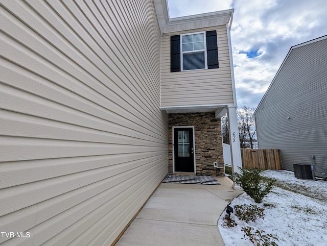 snow covered property entrance with central air condition unit