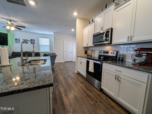 kitchen featuring decorative backsplash, white cabinetry, an island with sink, and appliances with stainless steel finishes