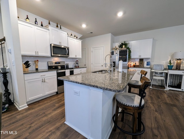 kitchen featuring backsplash, white cabinetry, dark stone counters, appliances with stainless steel finishes, and sink