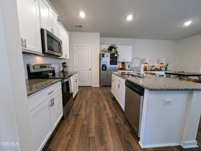 kitchen with stainless steel appliances, white cabinetry, sink, and an island with sink