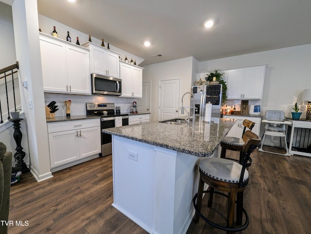 kitchen featuring dark hardwood / wood-style floors, a center island with sink, white cabinets, appliances with stainless steel finishes, and sink