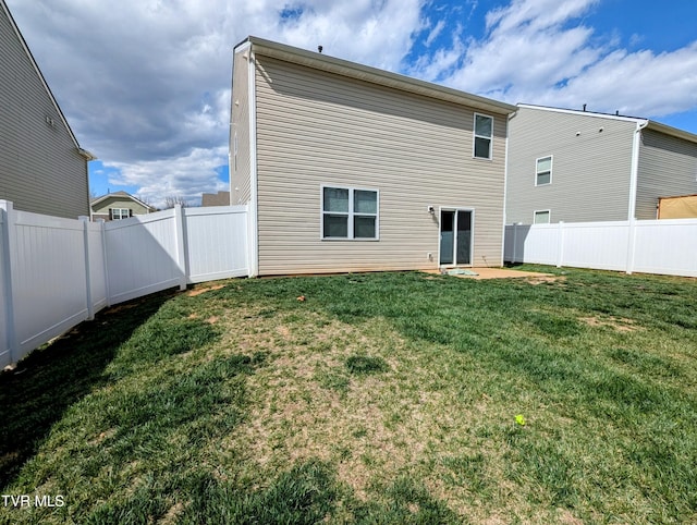 rear view of property featuring a fenced backyard and a yard