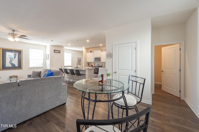 dining room featuring a textured ceiling, ceiling fan, dark wood-type flooring, and sink