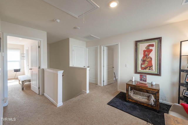 hall featuring light colored carpet and a textured ceiling