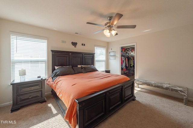 carpeted bedroom featuring a closet, a spacious closet, and ceiling fan