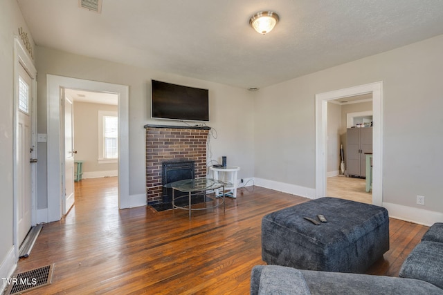 living room with a brick fireplace and hardwood / wood-style floors