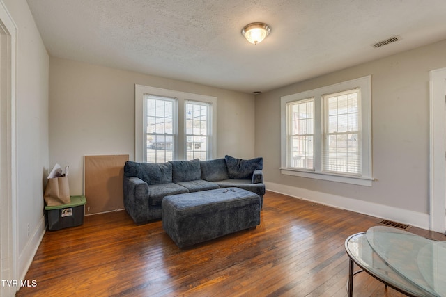 living room with dark hardwood / wood-style floors, a wealth of natural light, and a textured ceiling