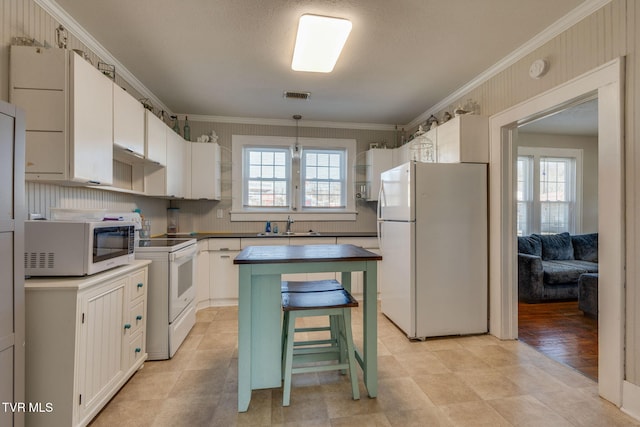 kitchen featuring white cabinetry, white appliances, ornamental molding, and a healthy amount of sunlight