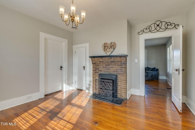 living room with a brick fireplace, hardwood / wood-style floors, and an inviting chandelier