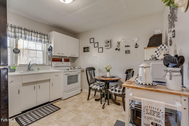 kitchen featuring sink, electric range, white cabinets, and a textured ceiling