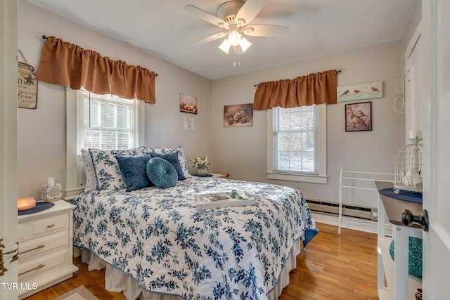 bedroom with ceiling fan, a baseboard radiator, and light hardwood / wood-style floors