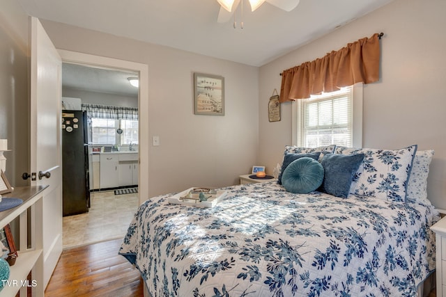 bedroom with black refrigerator, ceiling fan, and light wood-type flooring