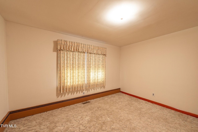 spare room with carpet flooring and a baseboard heating unit