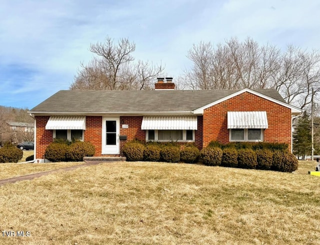 ranch-style house featuring a front yard, brick siding, and a chimney