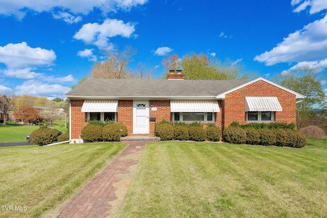 view of front of home featuring a chimney, a front lawn, and brick siding