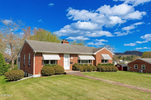 view of front of house featuring brick siding, a chimney, and a front lawn