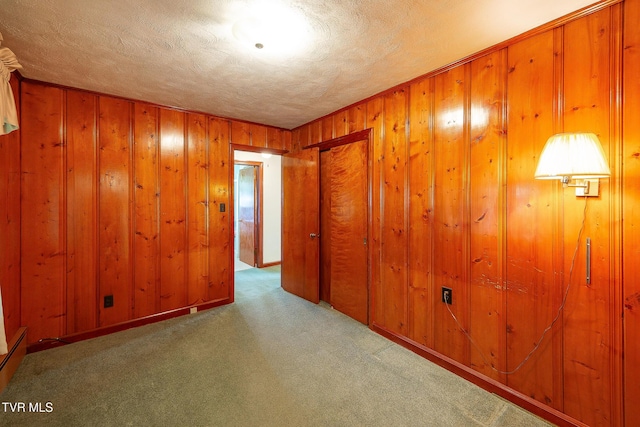 spare room featuring wooden walls, carpet, and a textured ceiling