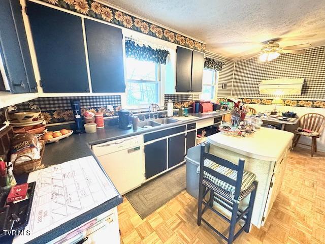 kitchen featuring a textured ceiling, white dishwasher, light parquet floors, ceiling fan, and sink