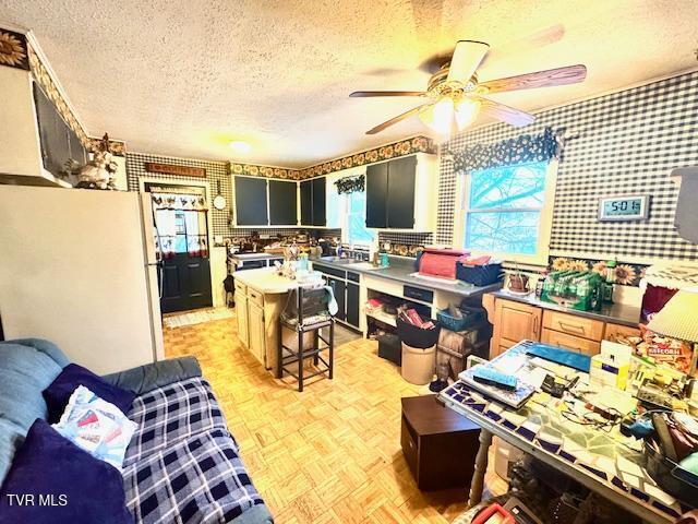 kitchen with a textured ceiling, light parquet floors, sink, a center island, and white fridge