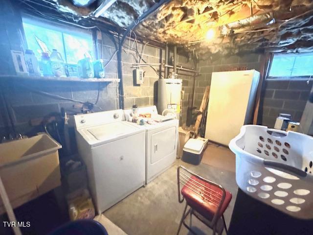 basement with a healthy amount of sunlight, gas water heater, sink, and washing machine and clothes dryer