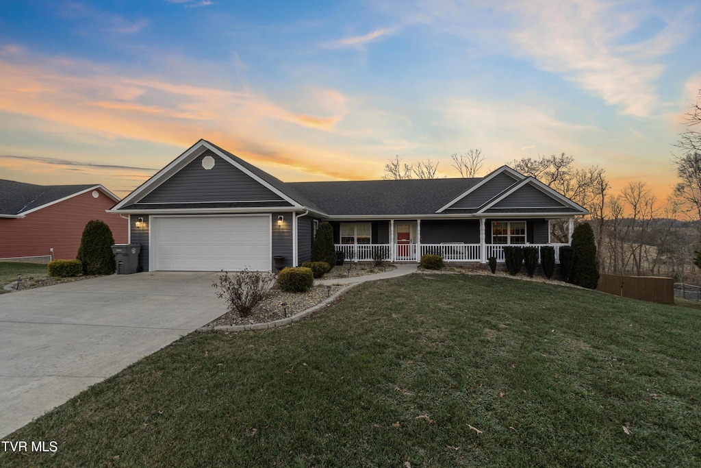 single story home with a lawn, a porch, and a garage