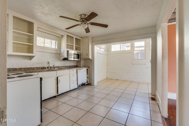 kitchen with a textured ceiling, white cabinetry, brick wall, and white appliances