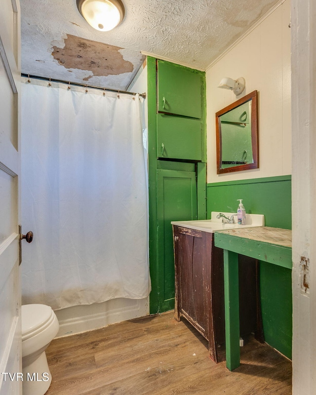 full bathroom with hardwood / wood-style floors, vanity, toilet, a textured ceiling, and shower / tub combo with curtain