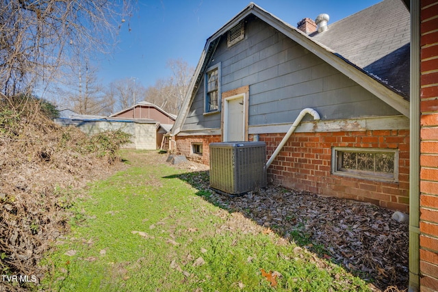 view of side of home featuring a lawn and central AC